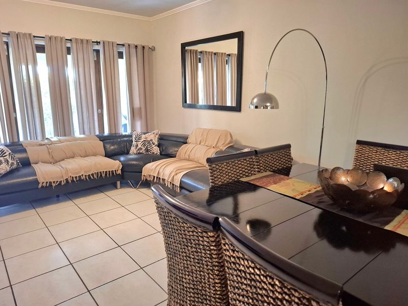 An open-plan living and dining area featuring neutral tiled flooring and large sliding glass doors that provide access to the exterior.