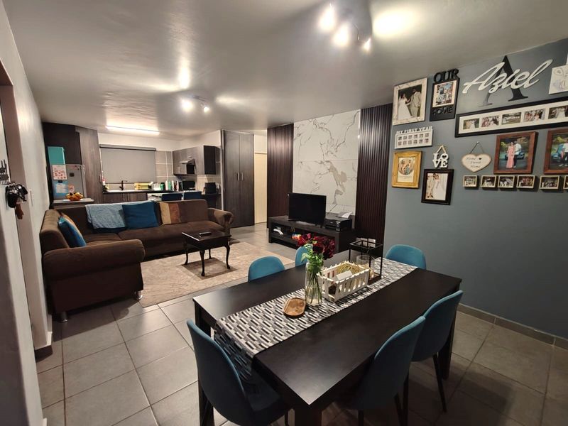 Spacious open-plan living and dining area featuring tiled floors, a modern feature wall, and an integrated kitchen layout.