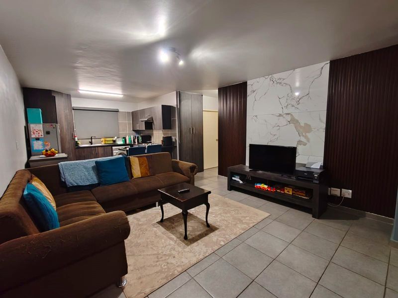 Open-plan living area featuring tiled floors, a modern feature wall with marble-effect cladding, and an integrated kitchen with built-in cabinetry.