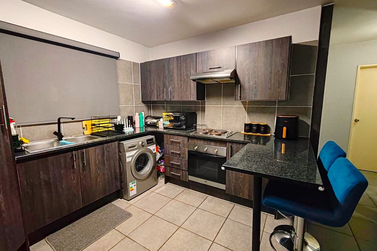 Modern kitchen featuring dark wood cabinetry, granite countertops, built-in oven with hob, extractor fan, and a convenient breakfast bar for casual dining.