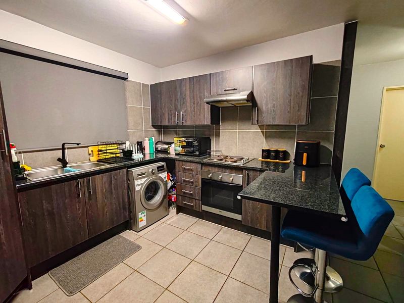 Modern kitchen featuring dark wood cabinetry, granite countertops, built-in oven with hob, extractor fan, and a convenient breakfast bar for casual dining.