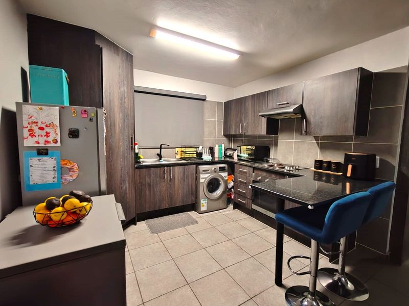 A functional kitchen featuring dark wood-look cabinetry, granite countertops, integrated appliances, and tiled finishes throughout.