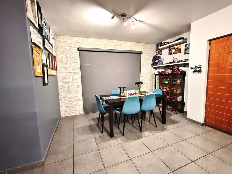 Dining area featuring tiled flooring, a stone veneer accent wall, and modern track lighting, creating a functional and well-defined space for meals.