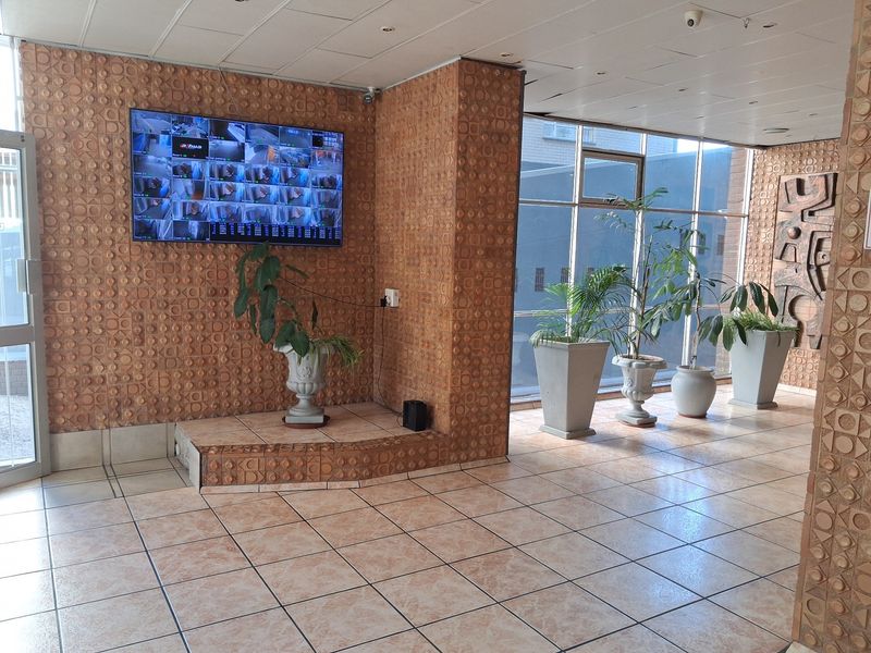 Spacious apartment entrance lobby featuring unique textured wall cladding, large windows for natural light, and tiled flooring throughout.