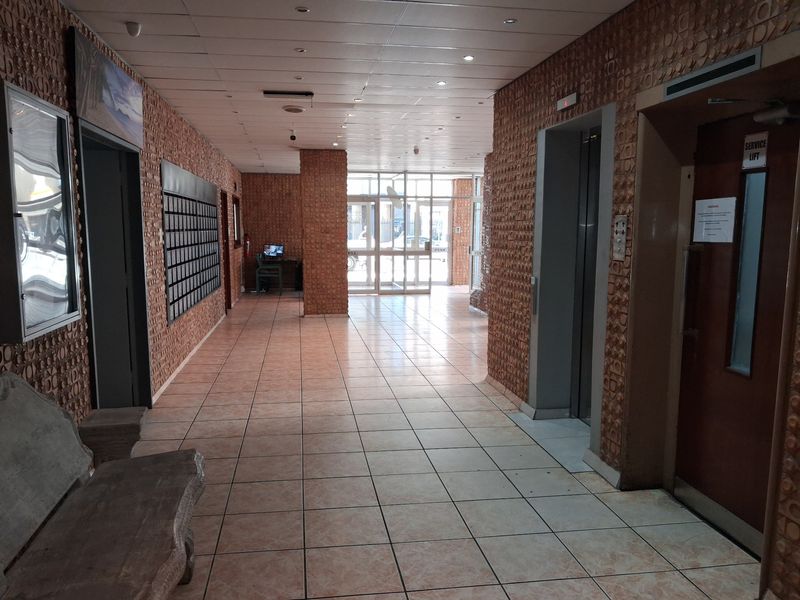 Spacious apartment building lobby featuring tiled flooring, elevator access, a service lift, and a bank of mailboxes.