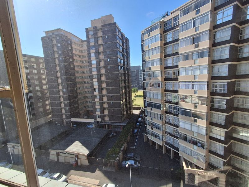 An elevated view looking out over a dense urban residential complex with multi-story apartment buildings and a shared parking area.