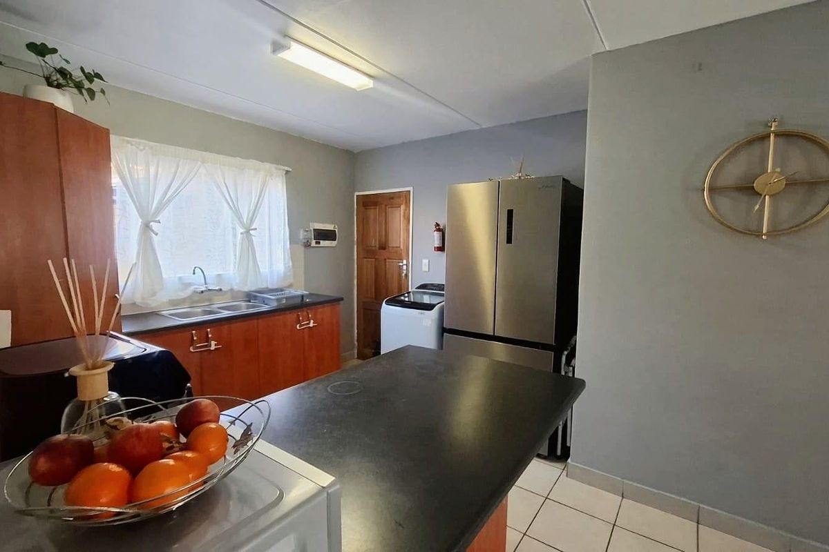 Functional kitchen featuring laminate countertops, double basin sink, built-in cabinetry, and tiled flooring, providing a practical workspace for daily meal preparation.