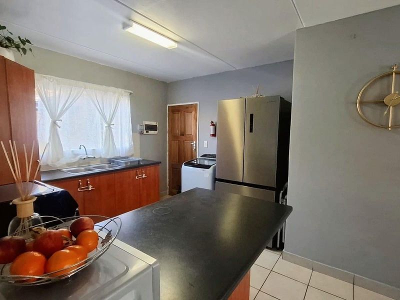 Functional kitchen featuring laminate countertops, double basin sink, built-in cabinetry, and tiled flooring, providing a practical workspace for daily meal preparation.
