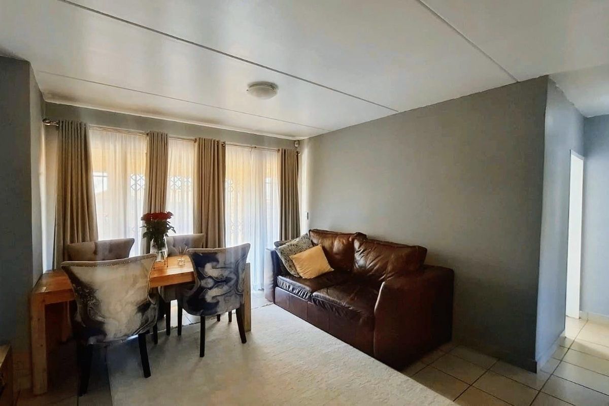 A living room area featuring tiled flooring, neutral wall tones, and a sliding glass door providing natural light.