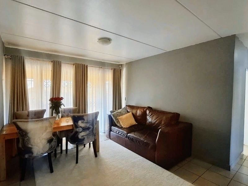 A living room area featuring tiled flooring, neutral wall tones, and a sliding glass door providing natural light.