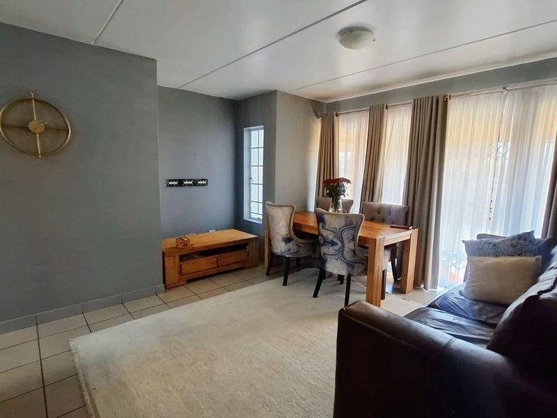 An open-plan living and dining area featuring tiled flooring and large sliding glass doors that provide access to the exterior.