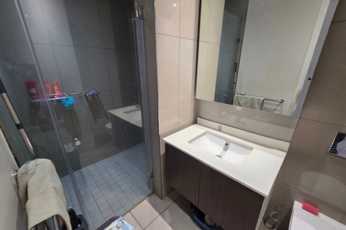 Modern bathroom featuring a glass-enclosed shower, wall-mounted vanity with integrated basin, and large wall mirror with neutral tiling throughout.
