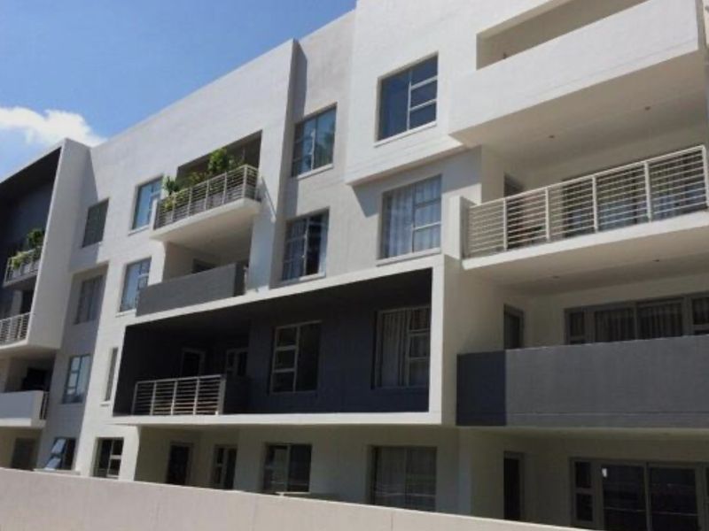 A modern apartment building exterior featuring clean architectural lines, multiple balconies with metal railings, and large windows.
