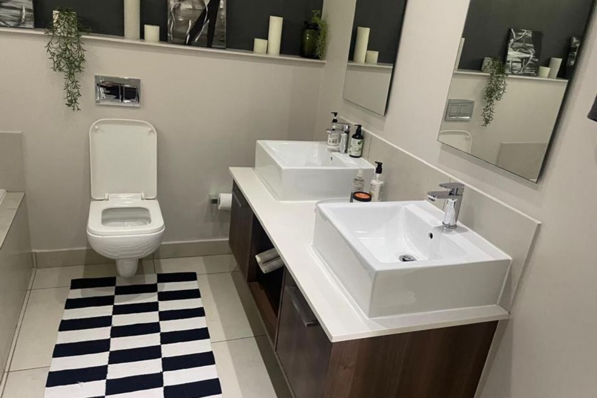 Modern bathroom featuring a double vanity with vessel sinks, wall-mounted toilet, and clean tiled finishes.