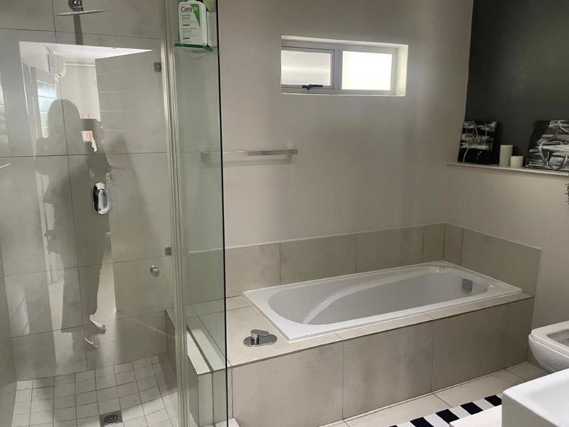 Modern bathroom featuring a glass-enclosed shower, a built-in bathtub with tiled surround, and neutral finishes.