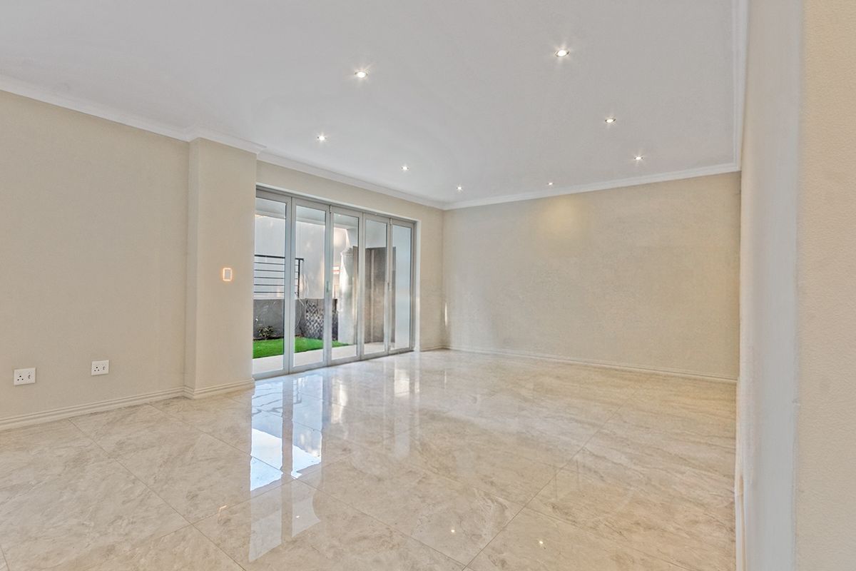 Spacious, empty living area featuring polished porcelain tile flooring, recessed downlighting, and large aluminium stacker doors providing access to the outdoor space.