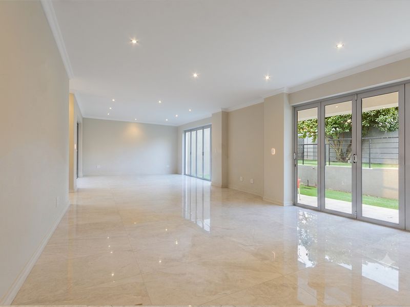 Spacious open-plan living area featuring polished porcelain tiles, recessed downlighting, and large aluminium stacker doors providing seamless access to the rear garden.