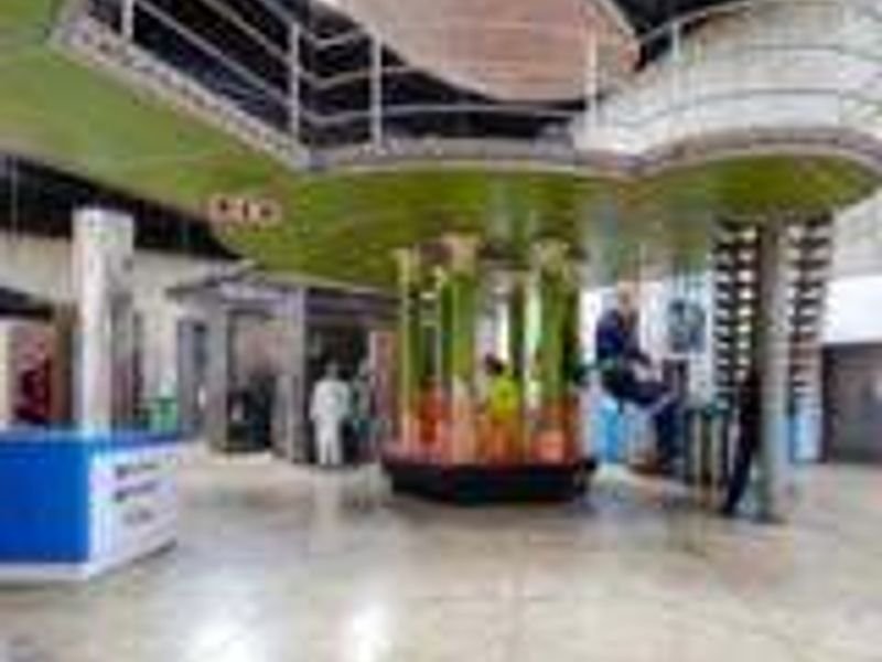 An industrial-style interior space featuring a mezzanine level with metal railings, tiled flooring, and prominent structural columns.
