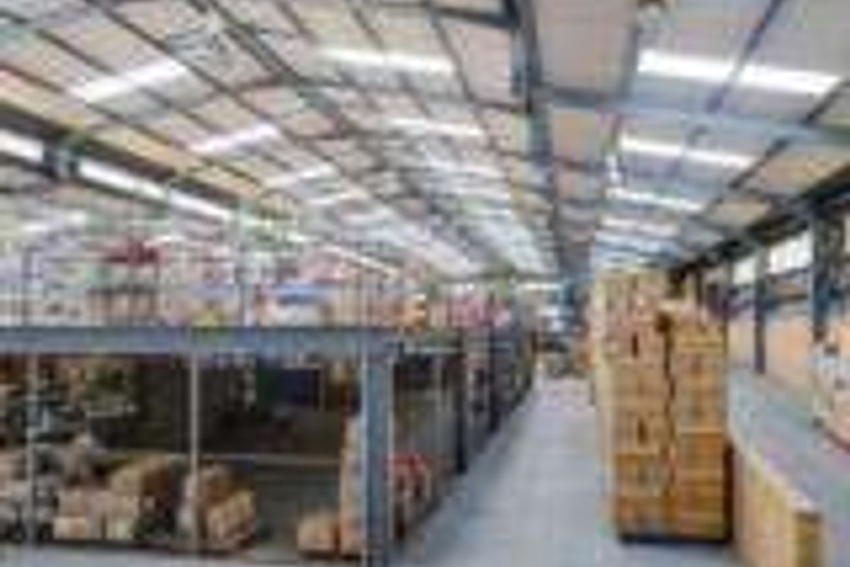 Spacious industrial warehouse featuring a steel portal frame, mezzanine storage level, concrete flooring, and ample natural light through roof skylights.