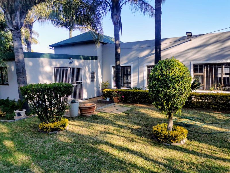Rear view of the property featuring a landscaped garden, paved walkway, and security-fitted windows and doors.