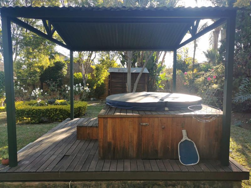 Outdoor entertainment area featuring a covered timber deck with a built-in spa, set within a landscaped garden.