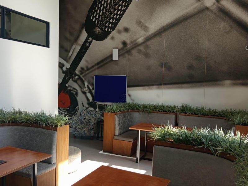 A modern office or co-working space featuring built-in booth seating with integrated power outlets and decorative fixed planters.