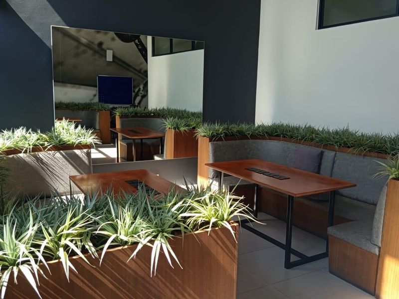 Modern communal lounge area featuring built-in bench seating, integrated wooden planters, and a large wall-mounted mirror, creating a sophisticated shared space.