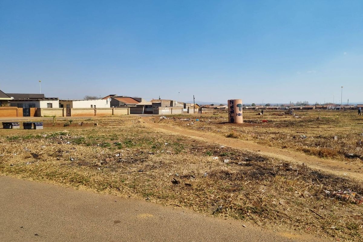 A vacant residential plot featuring direct road access and surrounding boundary walls, offering a blank canvas for future development in an established neighborhood.