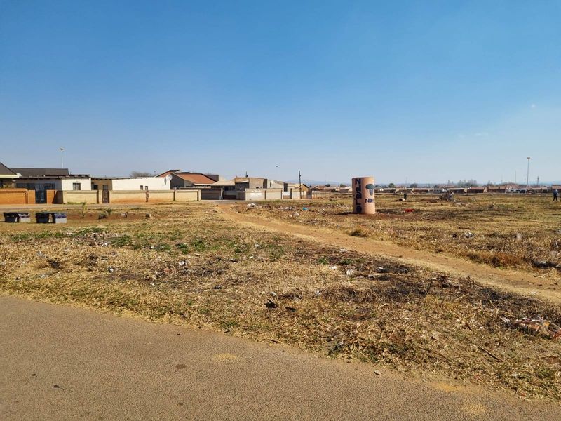 A vacant residential plot featuring direct road access and surrounding boundary walls, offering a blank canvas for future development in an established neighborhood.