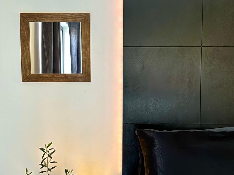 A modern bedroom featuring a sleek, dark, backlit headboard panel that creates a sophisticated and contemporary atmosphere.