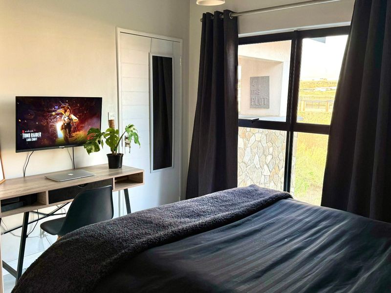 A well-maintained bedroom featuring a built-in wardrobe, large window with natural light, and neutral finishes, creating a comfortable and functional living space.