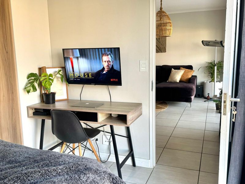 Bedroom featuring built-in wardrobes and tiled flooring, with a direct view into the adjacent living area through an open doorway.