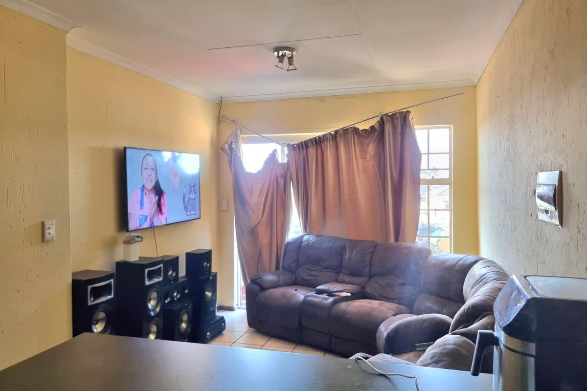 Living room area featuring tiled flooring and a window with a damaged curtain rod, requiring cosmetic updates to improve the overall condition.