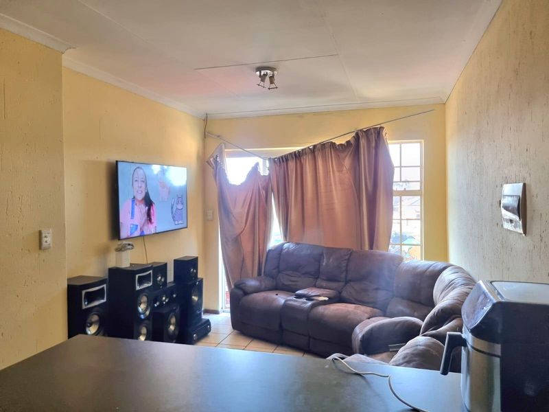 Living room area featuring tiled flooring and a window with a damaged curtain rod, requiring cosmetic updates to improve the overall condition.