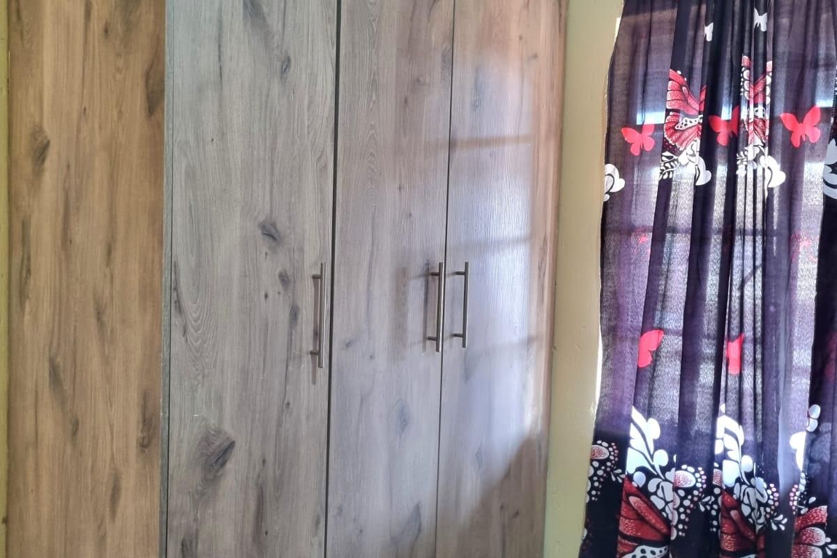 A bedroom featuring a modern wood-grain finish built-in wardrobe with sleek metal handles.