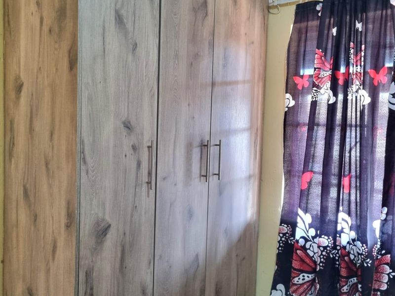 A bedroom featuring a modern wood-grain finish built-in wardrobe with sleek metal handles.