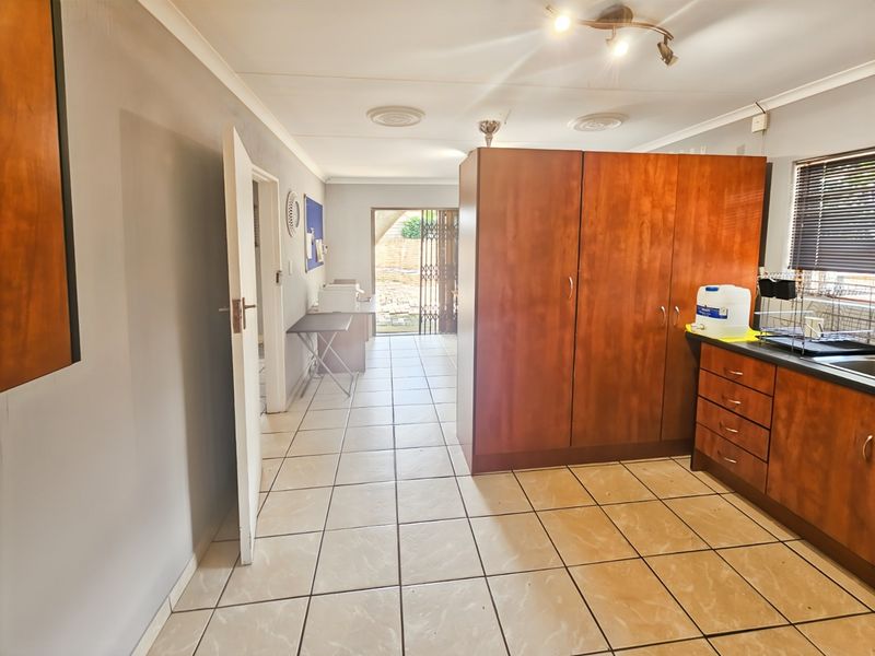 A functional kitchen area featuring built-in wooden cabinetry, tiled flooring, and direct access to an outdoor space through a security gate.