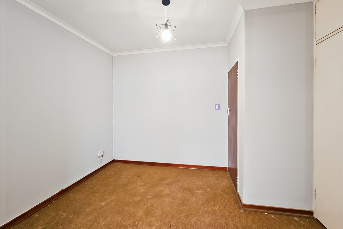 An empty bedroom featuring neutral walls, built-in cupboard storage, coving, and carpet flooring, providing a blank canvas for potential occupants.