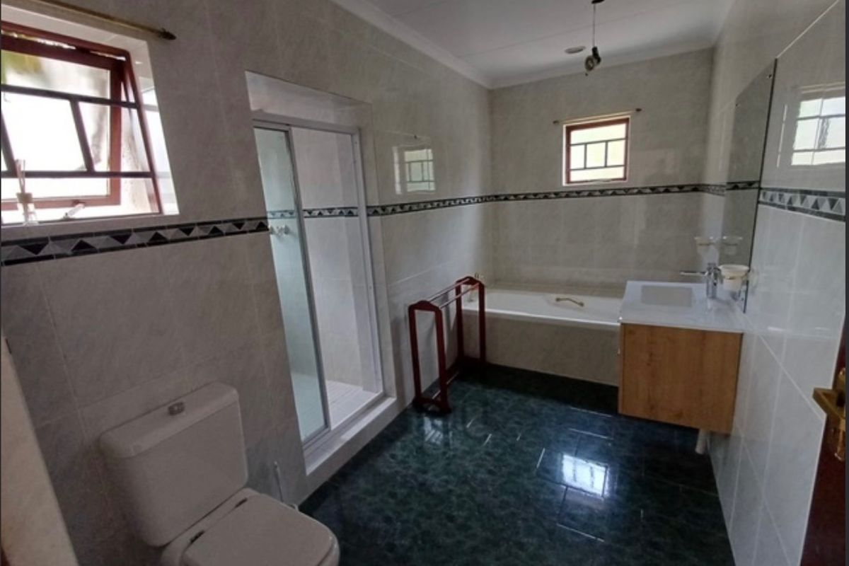 A functional bathroom featuring a shower enclosure, bathtub, vanity with basin, and toilet, finished with tiled walls and flooring.