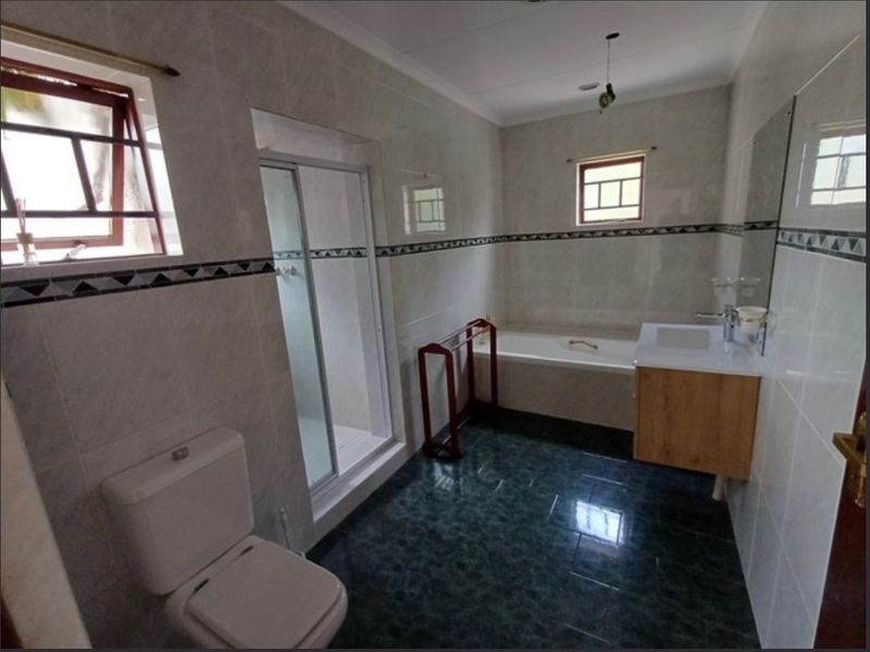 A functional bathroom featuring a shower enclosure, bathtub, vanity with basin, and toilet, finished with tiled walls and flooring.