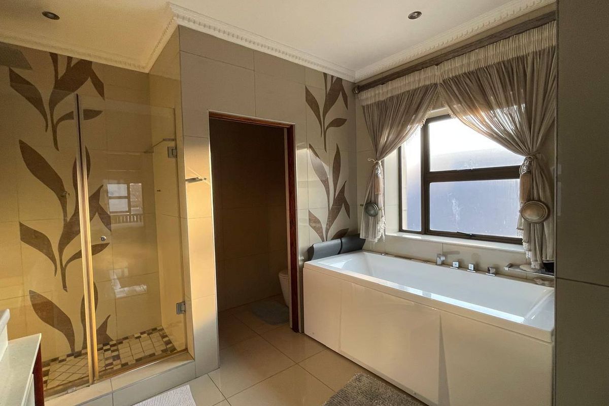 A well-maintained bathroom featuring a glass-enclosed shower, a built-in bathtub, and decorative wall tiling with recessed lighting.