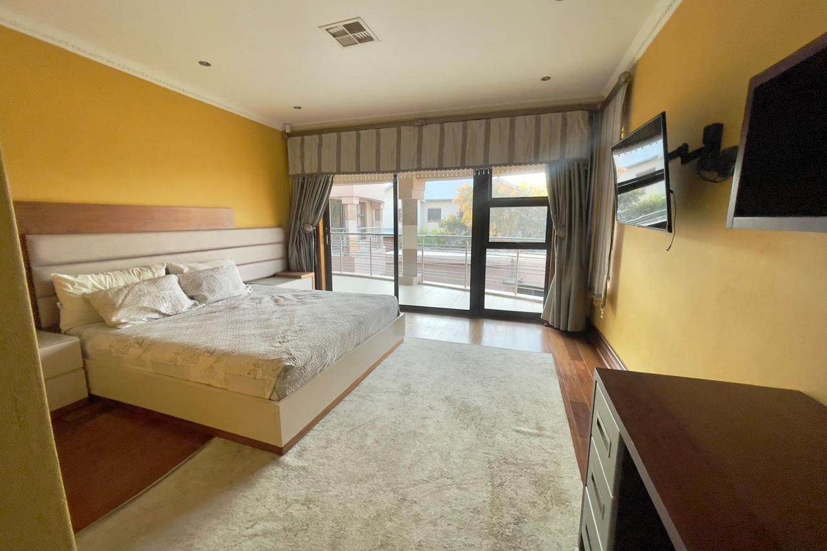 Spacious bedroom featuring hardwood flooring, recessed lighting, and large sliding glass doors providing direct access to a private balcony.