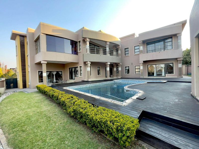 Spacious rear exterior featuring a modern swimming pool, extensive timber decking, and a multi-level residence with balconies and large glass sliding doors.
