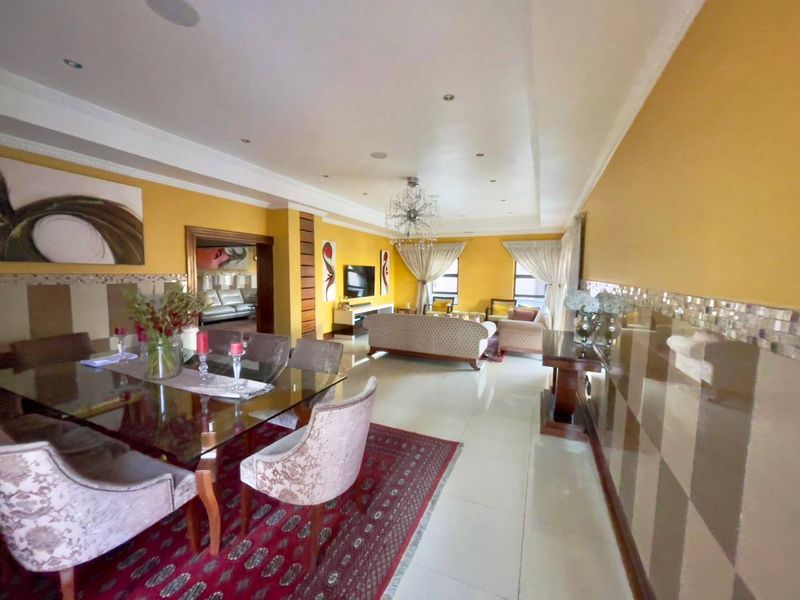 Spacious open-plan living and dining area featuring tiled floors, recessed ceiling lighting, and decorative wall accents, creating a versatile space for entertaining.