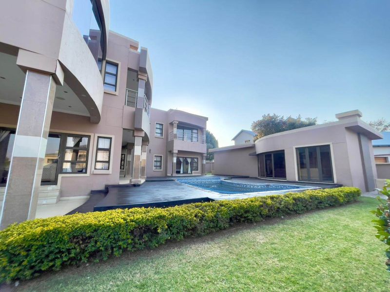 Rear view of a modern multi-story house featuring a swimming pool, dark timber decking, and a well-maintained garden area.