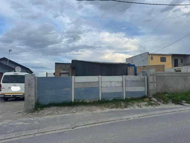 Front view of the property featuring a precast concrete boundary wall and brick facade, showing signs of wear and weathering.