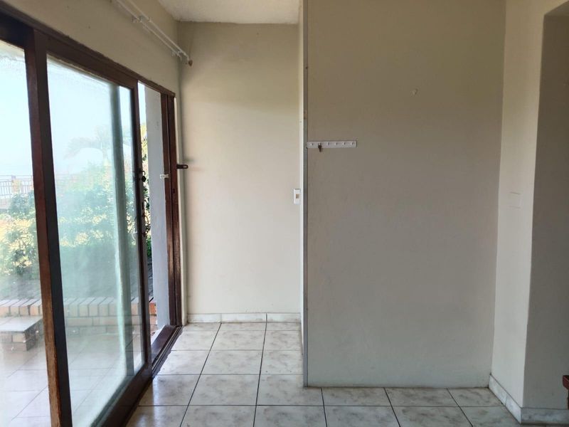 An empty living area featuring ceramic floor tiles and a large sliding glass door providing access to the outdoor patio.