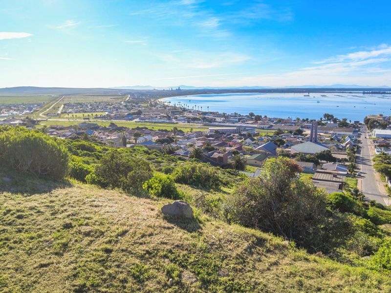 An elevated aerial view overlooking a coastal town, residential area, and the surrounding landscape.