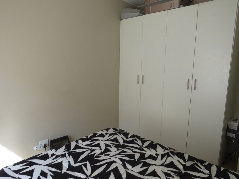 A bedroom featuring a white built-in wardrobe with modern handles, providing ample storage space.