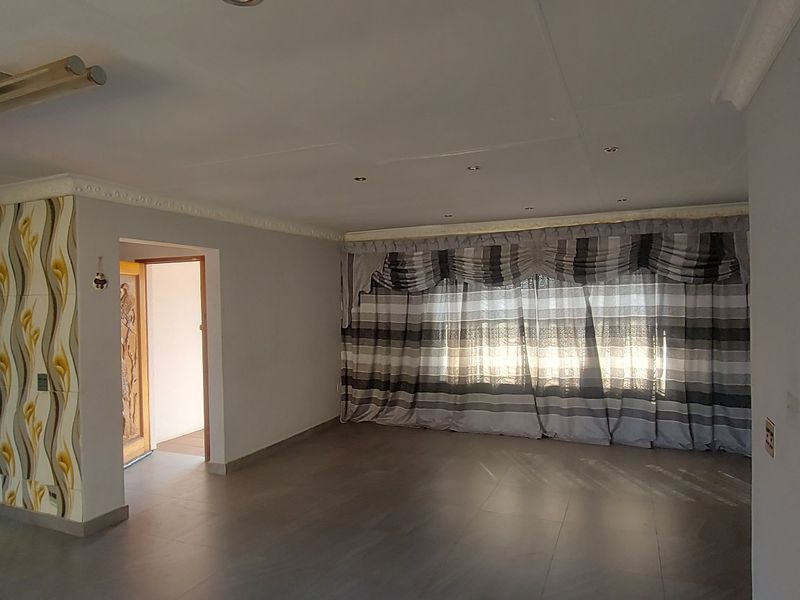 Spacious open-plan living area featuring tiled flooring, recessed lighting, and a functional kitchen with built-in cabinetry and appliances.